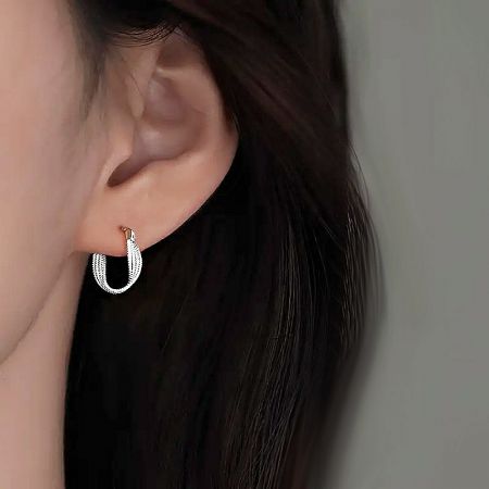 Side view of the 925 sterling silver twisted huggie earring on an ear, highlighting its elegant curve.