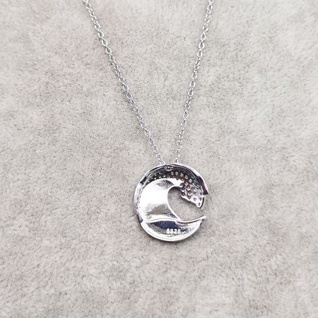 Side profile of the sterling silver wave necklace pendant, highlighting its elegant curve.