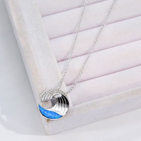 Full view of the silver wave necklace with its vibrant blue opal pendant.