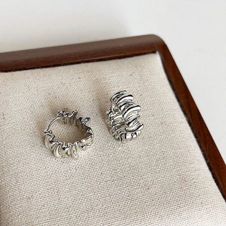 Two pairs of the irregular pleated silver earrings displayed to show different angles.