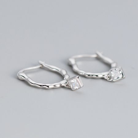 Side profile of the silver wavy hoop earrings highlighting the texture and clear gemstone.