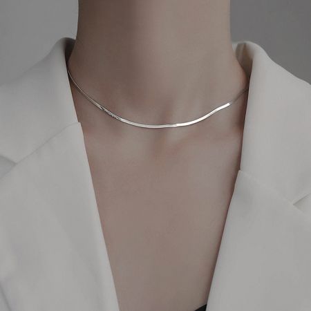 Detailed view of the silver herringbone snake chain necklace on a model, highlighting its flat and smooth texture.
