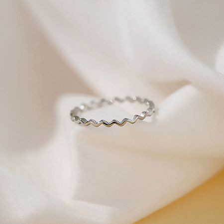 Close-up of a single 925 silver waving line ring on a white textured background.
