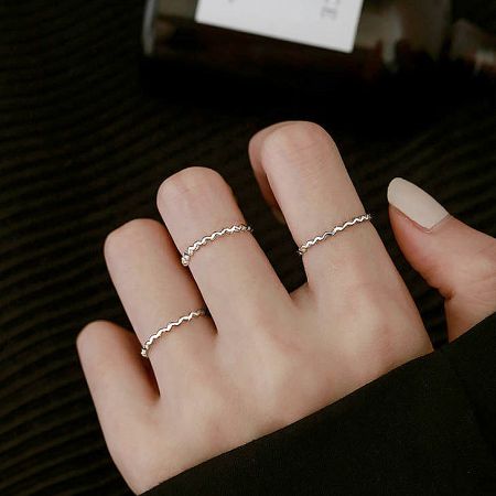 A model's hand elegantly displaying four rings from the 925 silver stackable set.