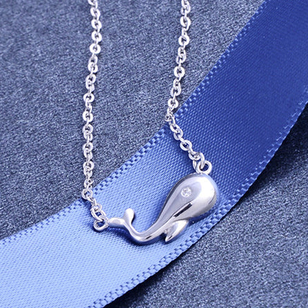 The whale pendant necklace presented with a decorative blue ribbon.