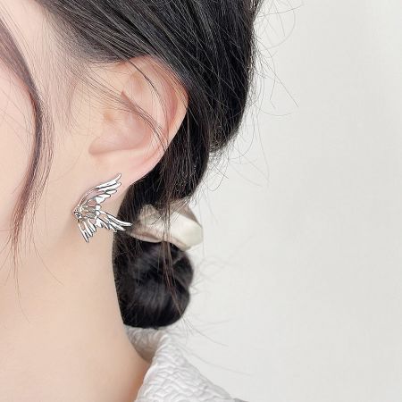 Close-up of a woman wearing a silver-plated butterfly stud earring, showcasing its delicate design.