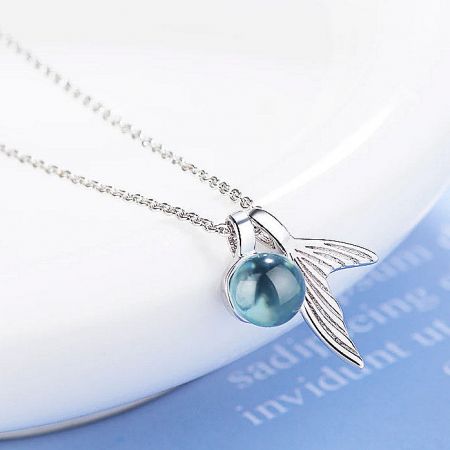 Silver necklace with a unique winged pendant and a central blue orb.