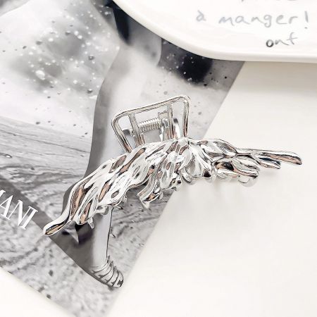 A sleek silver hair clip with an intricate winged design.