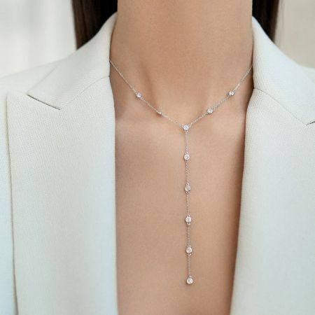Detailed view of the silver Y-shaped necklace with sparkling cubic zirconia accents, worn with an elegant white blazer.