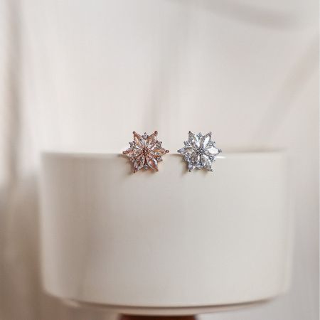 A pair of snowflake-designed earrings in rose gold and silver finishes.