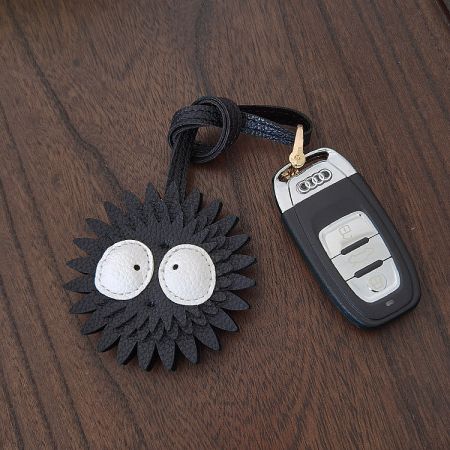 Soot Sprite leather keychain attached to an Audi car key fob, demonstrating its use as a car key holder.