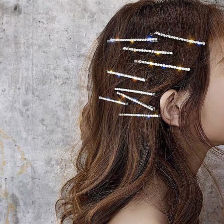 Multiple sparkling rhinestone hairpins beautifully arranged in a woman's hair for a glamorous effect.