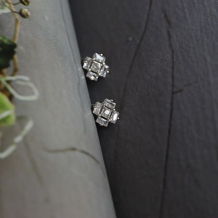 A pair of silver ice cube earrings with clear gemstones arranged in a square pattern.