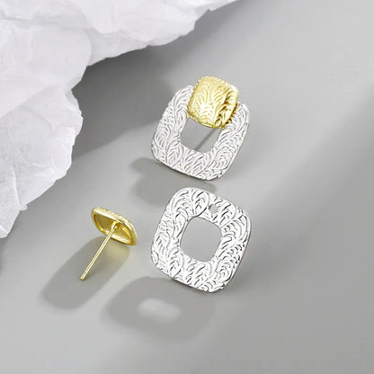 Close-up of the textured silver finish and gold accents on the geometric hollow square earrings.