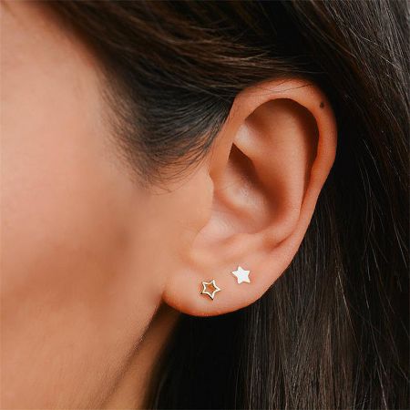 A model showcasing the 925 sterling silver star stud earrings in both gold and silver on her ear.