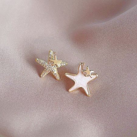 A pair of gold-plated star-shaped earrings, one with a white gemstone center.