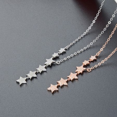 A collection of three star-themed necklaces in silver and rose gold finishes.