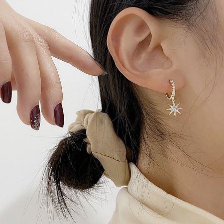 Lifestyle product photo of the starburst huggie earring being worn.