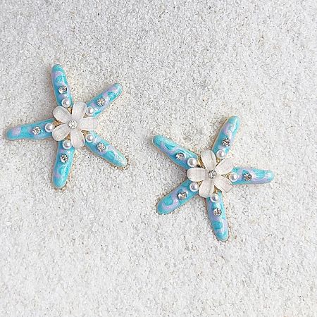 A close-up view of the starfish earrings, showing the intricate enamel work, pearl, and gemstone details.