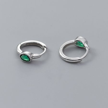 Detailed view of sterling silver huggie hoops with vibrant green oval gemstones.