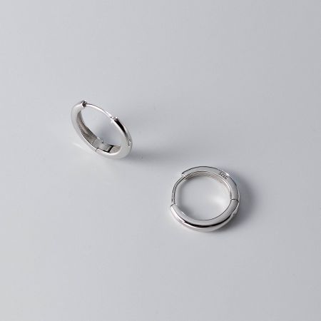 Detailed shot of the sterling silver hoop earrings, highlighting the '925' stamp that certifies the material's purity.