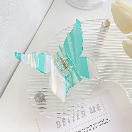 A detailed view of a teal and white striped butterfly hair clip.