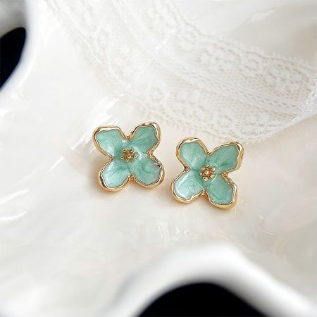 Close-up of the flower-shaped stud earrings with teal enamel and gold trim.