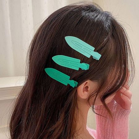 A close-up view of a set of three teal-colored no-crease metal hair clips.