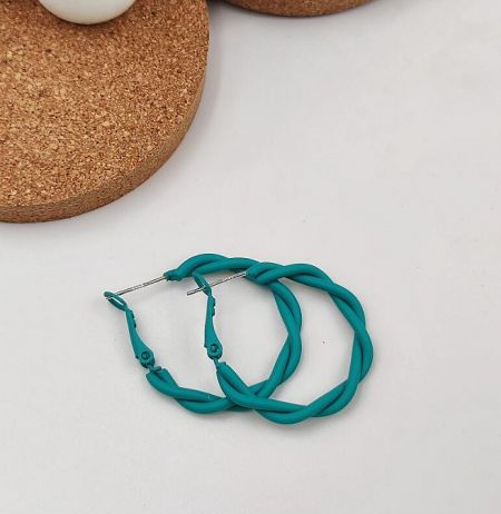 Close-up of a pair of twisted teal enamel earrings with gold post.