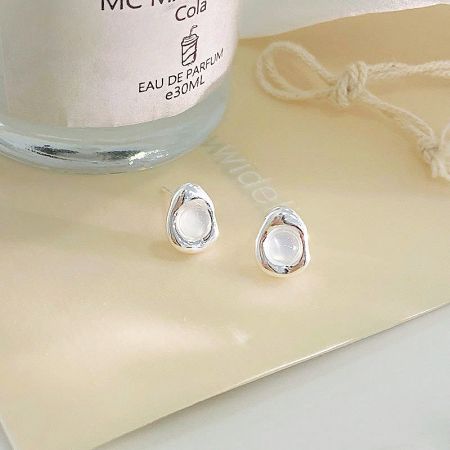 Elegant teardrop-shaped opal earrings presented alongside a luxury perfume bottle.