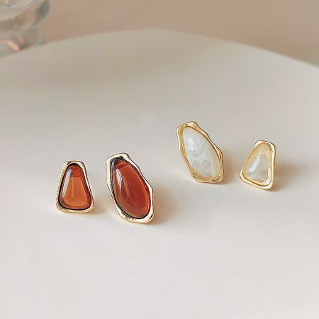 A set of four jewelry pieces featuring teardrop-shaped stones in orange and white.