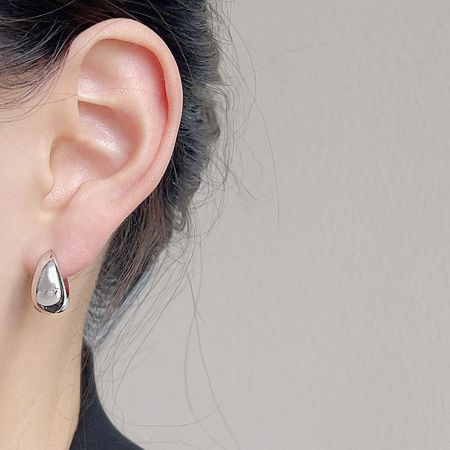 Close-up of a woman wearing the silver teardrop hoop earring.