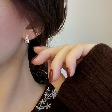 A close-up of the teardrop silver earring on a model, emphasizing its sparkle and craftsmanship.