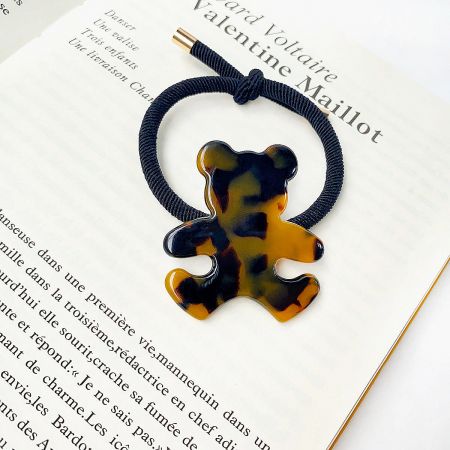 A stylish tortoiseshell pattern bear charm attached to a black elastic hair tie.