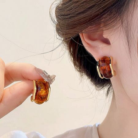 Gold-Plated Amber Textured Acrylic C-Shape Stud Earrings (Set of 5 Pairs) - A woman wearing and holding a pair of elegant tortoiseshell C-shape stud earrings with gold accents, showcasing their stylish design.