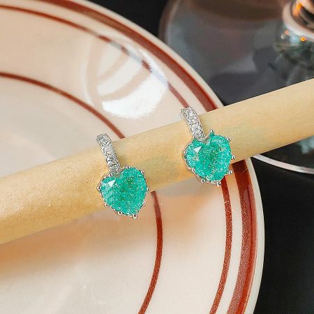 Detailed shot of the heart-shaped turquoise stone earring with textured surface and silver setting.