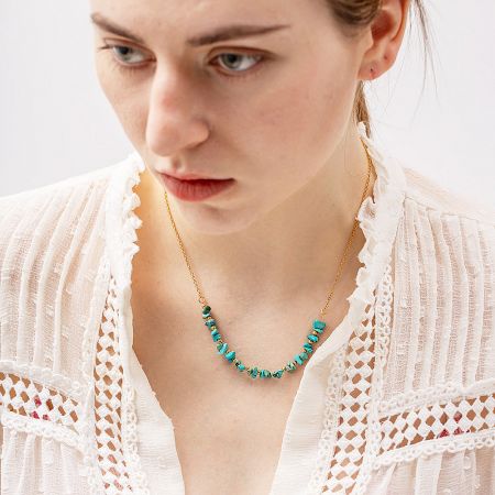 Close-up of the turquoise bead necklace on a model, highlighting the stone's natural texture and gold chain.