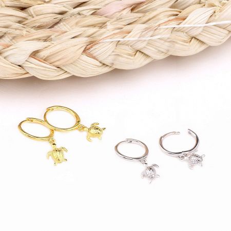 925 스털링 실버 바다 거북이 허기 후프 귀걸이 - 925 스털링 실버 바다 거북이 허기 후프 귀걸이 한 쌍이 금색과 은색 마감으로 보여지며, 상세한 거북이 참 디자인을 강조합니다.