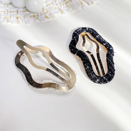 A pair of unique hair clips featuring textured borders and metallic bases.