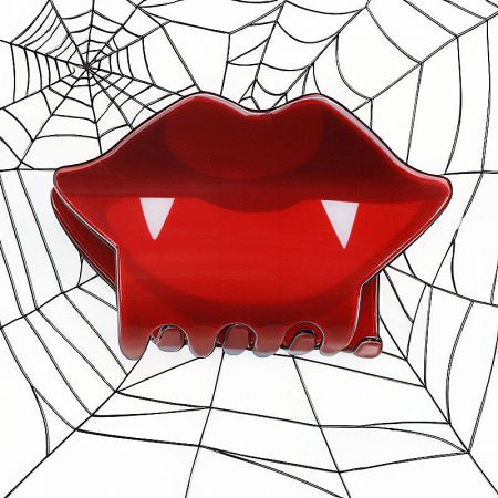Vampire lips and fangs design on a spooky Halloween hair clip.
