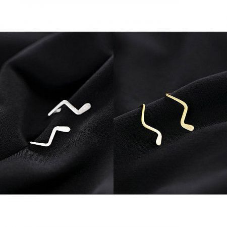 Two pairs of wavy line earrings in silver and gold, highlighting the minimalist design.