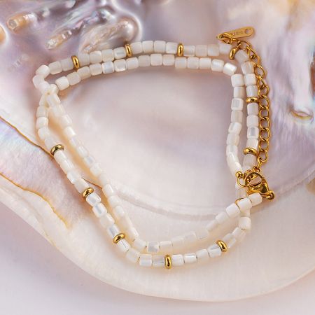 A matching white beaded bracelet with a seashell charm, perfect for a complete look.