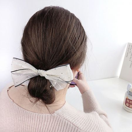 A delicate white bow hair accessory, perfect for a classic, vintage look.