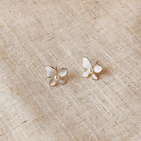 Detailed shot of the white butterfly stud earring highlighting the gold accents and pearl center.