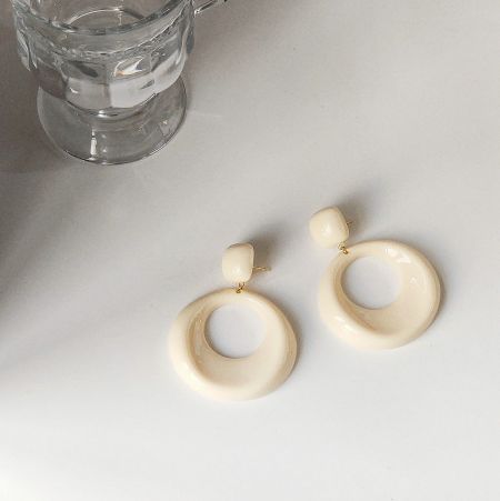 A pair of chic white circular earrings with elegant gold posts.