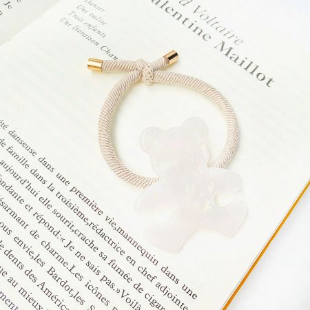 A simple and elegant white bear charm on a white elastic band with gold-tone hardware.