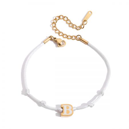 Detailed view of the white cord friendship bracelet featuring a gold and white enamel 'B' initial charm.