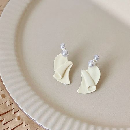 A pair of white leaf-shaped earrings with pearl accents on a neutral background.