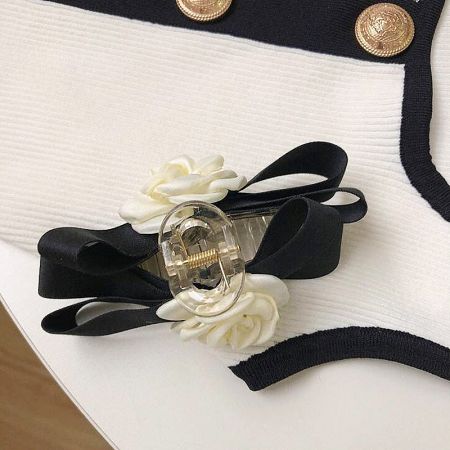 Detailed view of the fabric and craftsmanship of the white camellia and black ribbon hair accessory.