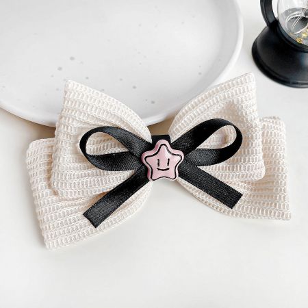 Close-up of a white knitted fabric hair bow with a pink star charm.